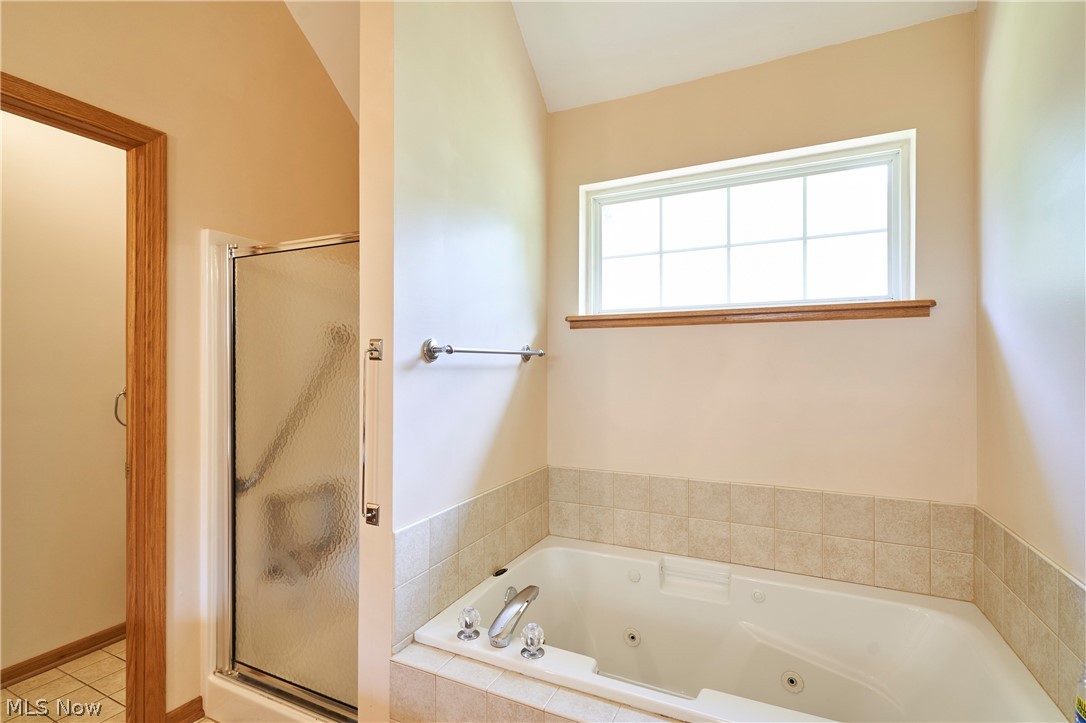 1963 Haines Road Madison, OH 44057 - Photo 13 of 34 Bathroom featuring a built-in jetted tub, tiled surround, glass-enclosed shower, and a high-set window