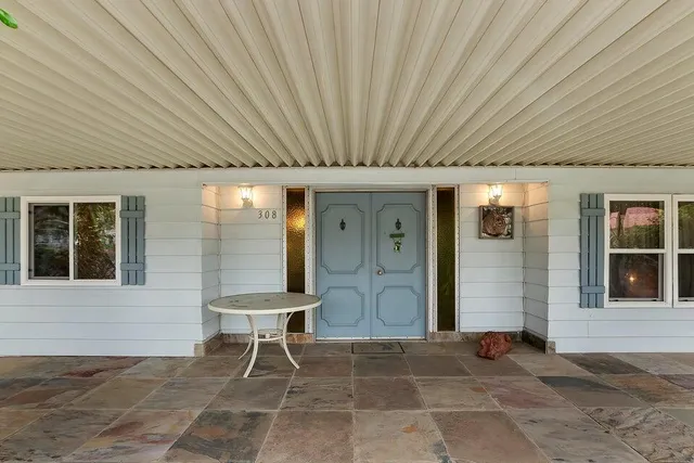a porch with a table and chairs and potted plants
