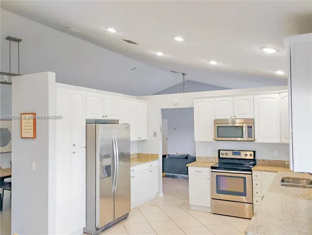 a kitchen with granite countertop white cabinets and stainless steel appliances