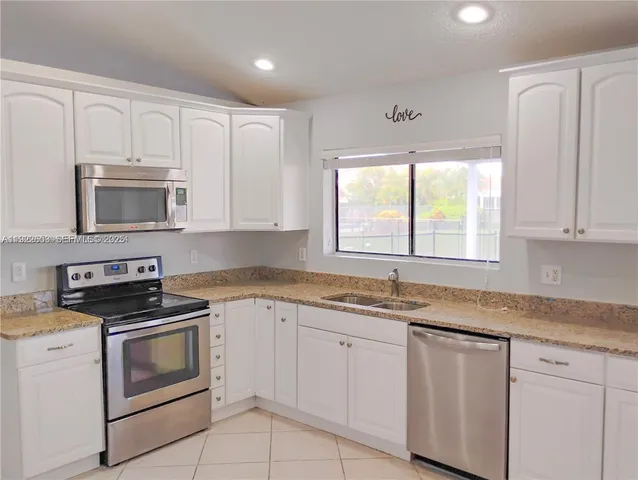 a kitchen with granite countertop white cabinets sink and window