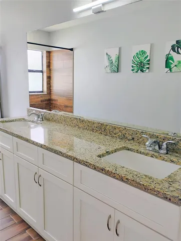 a bathroom with a granite countertop double vanity sink and mirror