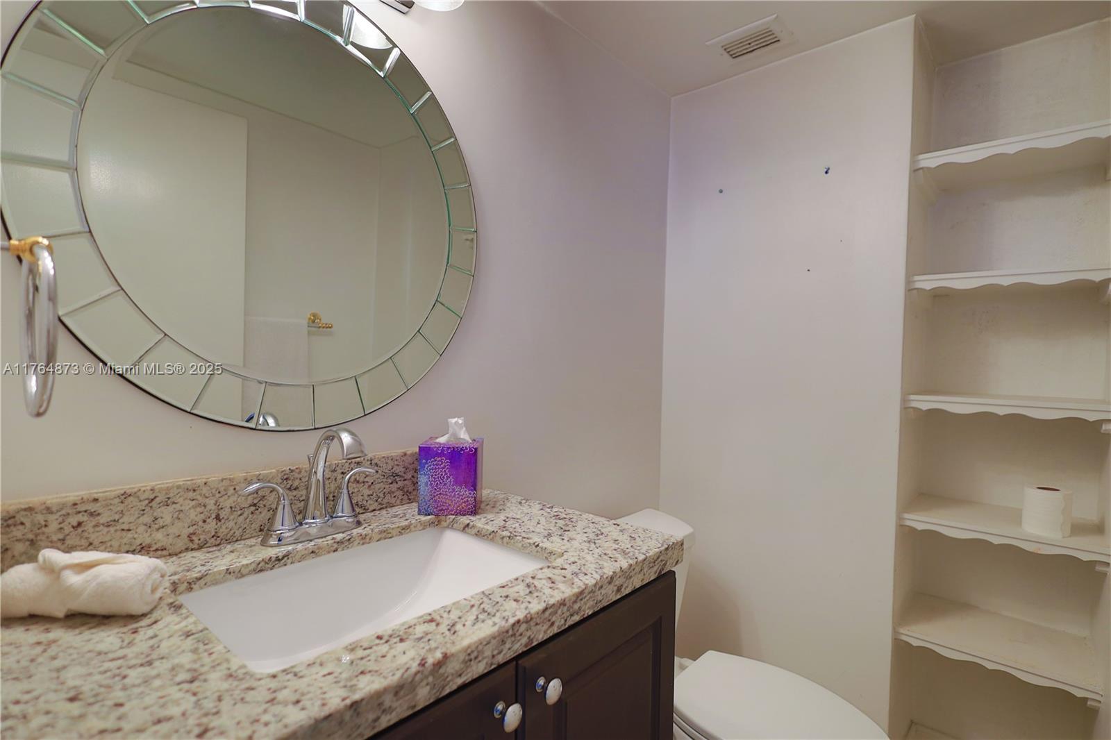 9225 Collins Avenue, Unit 503 Surfside, FL 33154 - Photo 14 of 37 a bathroom with a granite countertop sink a mirror and toilet