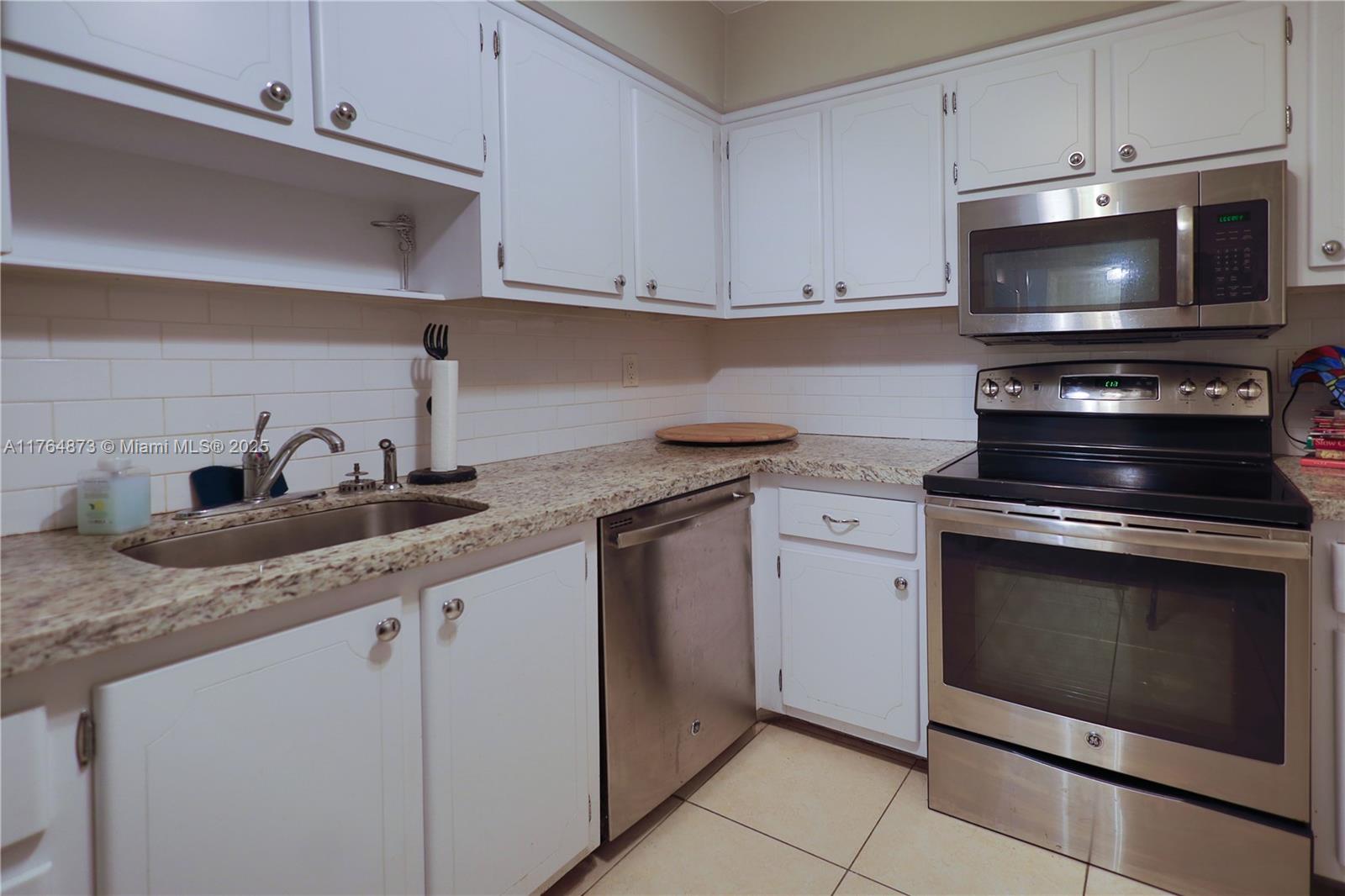 9225 Collins Avenue, Unit 503 Surfside, FL 33154 - Photo 17 of 37 a kitchen with granite countertop a stove top oven microwave and cabinets