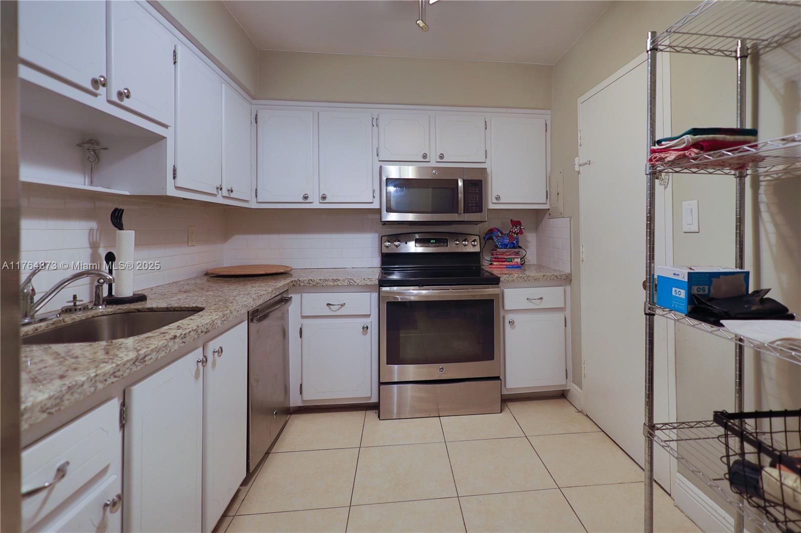 9225 Collins Avenue, Unit 503 Surfside, FL 33154 - Photo 19 of 37 a kitchen with stainless steel appliances granite countertop a sink stove and microwave