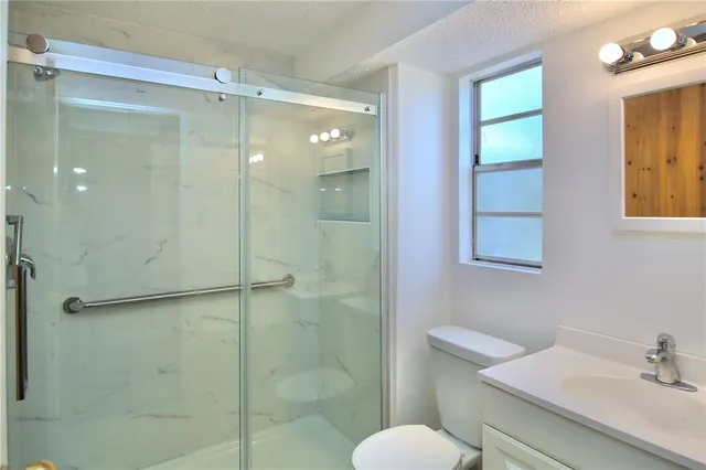 a bathroom with a shower sink vanity and toilet