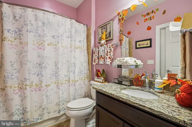 a bathroom with a granite countertop sink and a toilet