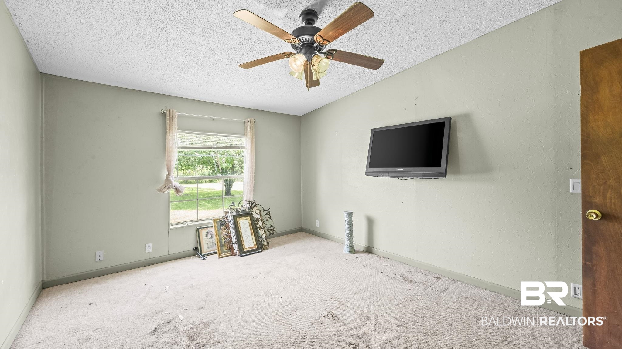 34985b Spring Road South, Unit B Stapleton, AL 36578 - Photo 11 of 31 Carpeted room featuring a ceiling fan with integrated lighting, a single window, and a wood-finish door