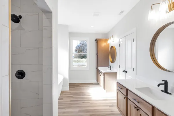 a bathroom with a tub sink mirror and shower