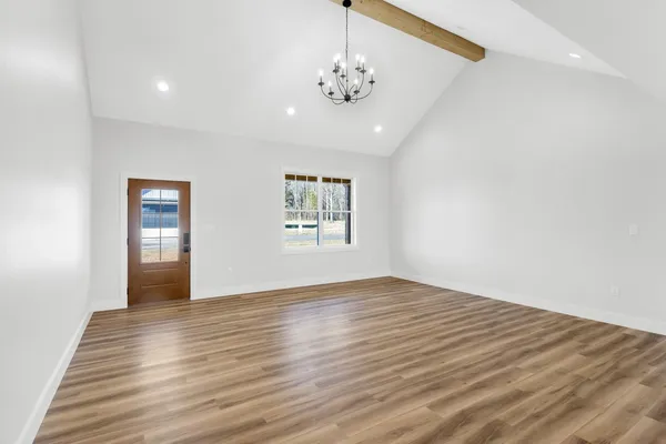 an empty room with wooden floor chandelier and windows
