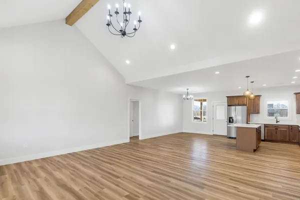 a view of kitchen and empty room with wooden floor