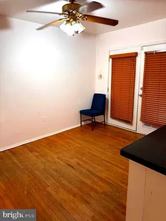 a view of a room with wooden floor and a ceiling fan