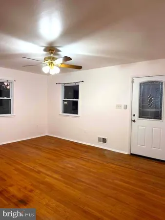 a view of an empty room with window and wooden floor