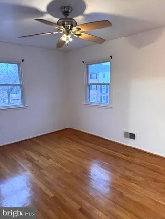 a view of an empty room with chandelier fan and wooden floor