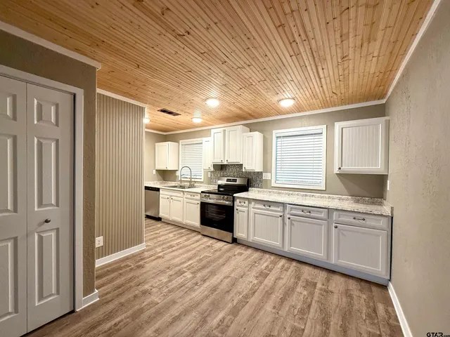 a large kitchen with kitchen island white cabinets and stainless steel appliances