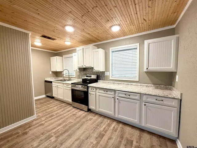 a kitchen with granite countertop white cabinets a sink a window and stainless steel appliances