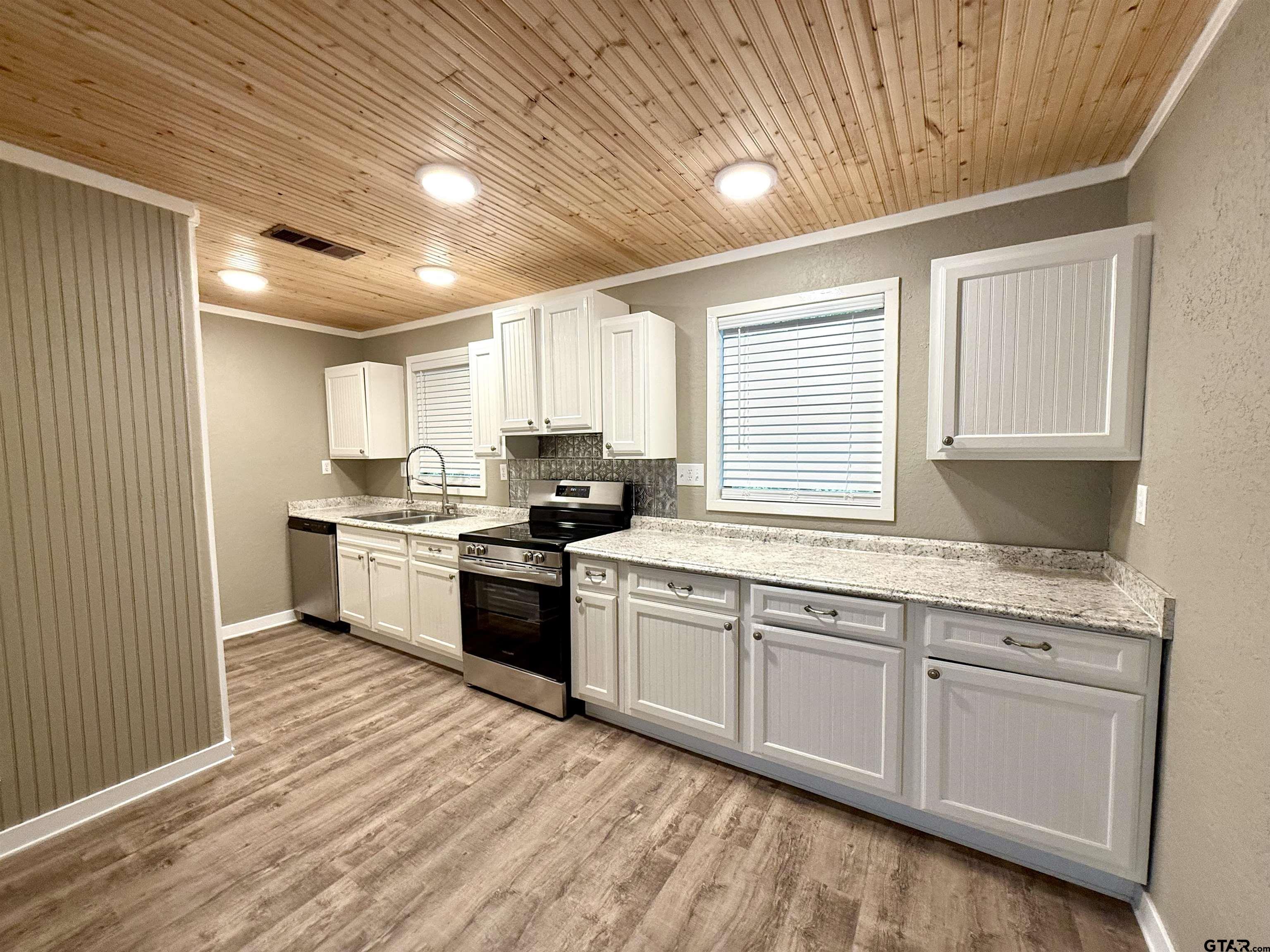 449 Rs Private Road Emory, TX 75440 - Photo 5 of 20 a kitchen with granite countertop white cabinets a sink a window and stainless steel appliances