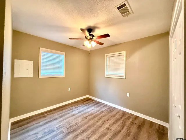 a view of a room with wooden floor and a ceiling fan