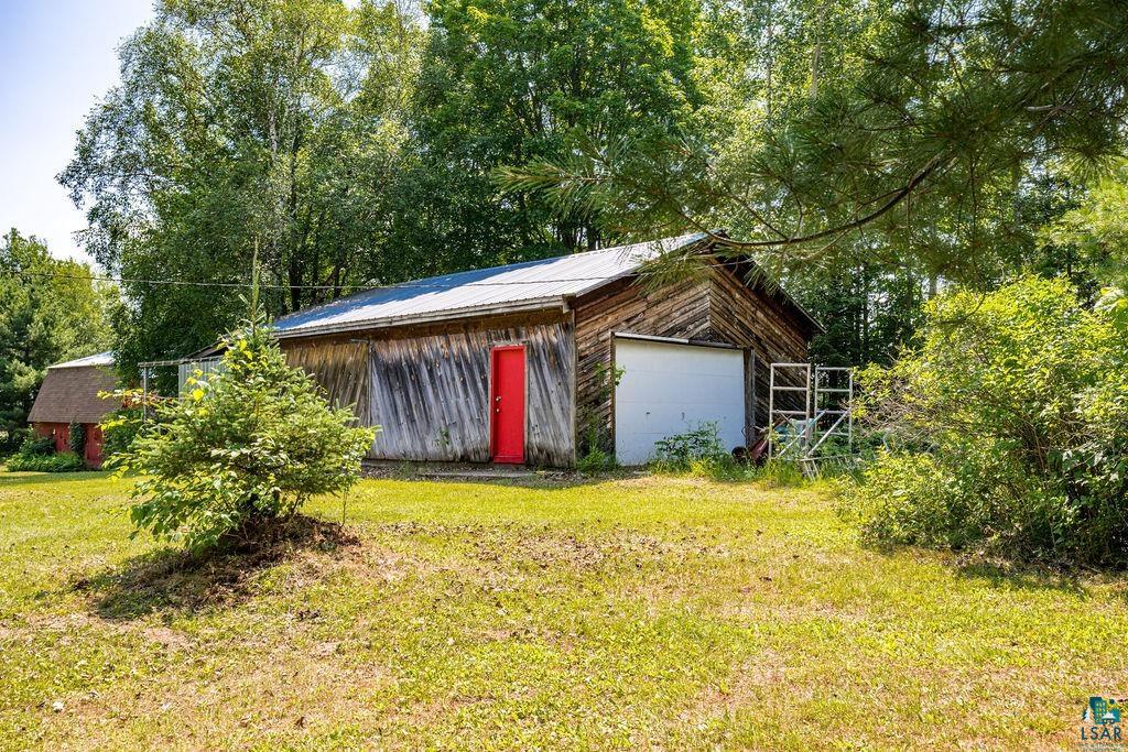 2592 Strandberg Road Barnum, MN 55707 - Photo 21 of 44 Wood-sided outbuilding featuring a metal roof, red door, and a white overhead door