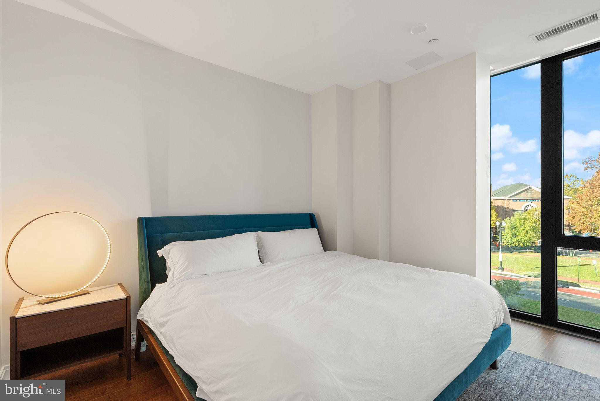 1111 Pennsylvania Ave. Southeast, Unit 304 Washington, DC 20003 - Photo 11 of 42 a bedroom with a bed a lamp and window