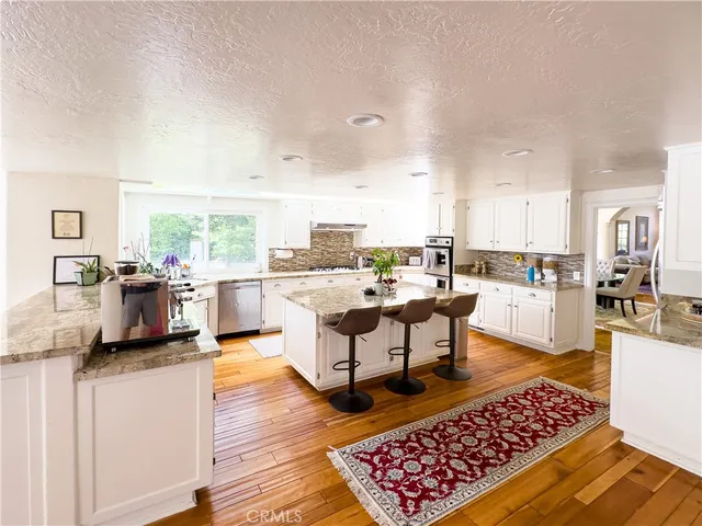 a living room with stainless steel appliances kitchen island granite countertop a sink and cabinets