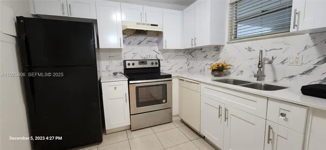 a kitchen with stainless steel appliances a refrigerator stove and white cabinets