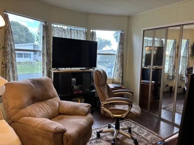 a living room with furniture a flat screen tv and a floor to ceiling window