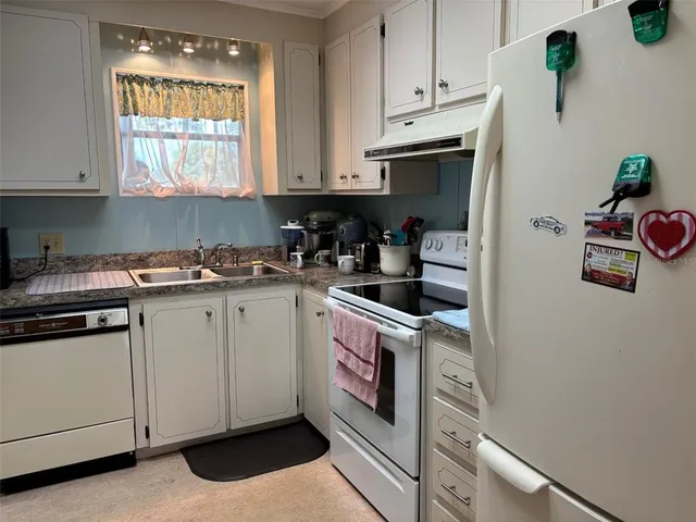 a kitchen with stainless steel appliances granite countertop white cabinets and window
