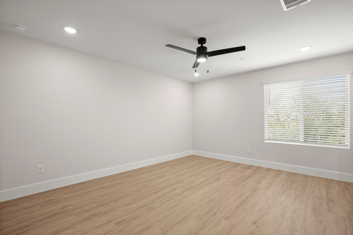 17407 Homestead Haven Drive Bee Cave, TX 78738 - Photo 13 of 16 an empty room with wooden floor ceiling fan and windows