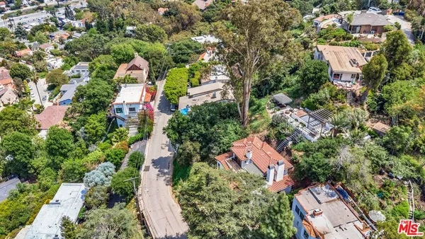 an aerial view of residential houses with outdoor space and trees all around
