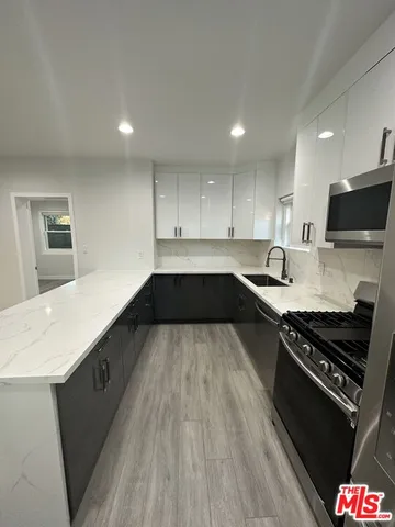 a large kitchen with stainless steel appliances granite countertop a stove a sink and a refrigerator