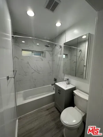 a bathroom with a toilet sink vanity and shower
