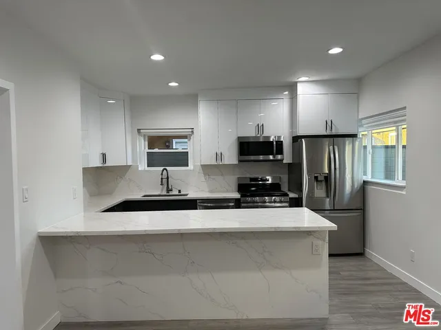 a kitchen with stainless steel appliances a sink a stove a microwave a refrigerator a sink a refrigerator and cabinets