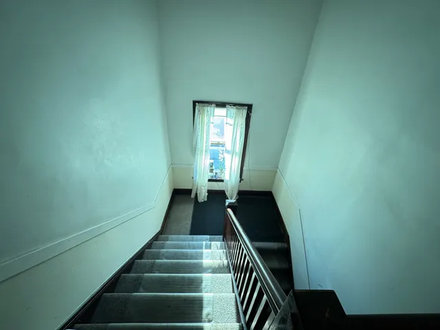 a view of a staircase with wooden floor and white walls