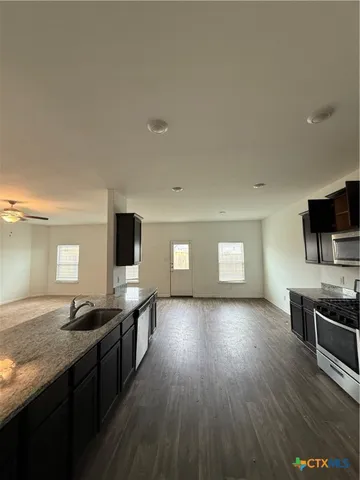 a kitchen with stainless steel appliances granite countertop wooden cabinets a stove top oven a sink and dishwasher