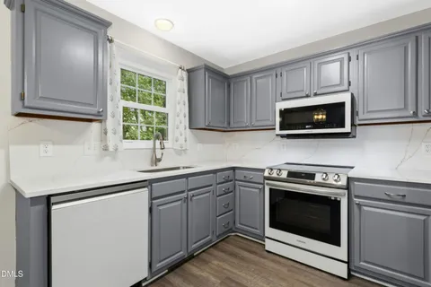 a kitchen with stainless steel appliances granite countertop a sink a stove a microwave and wooden cabinets