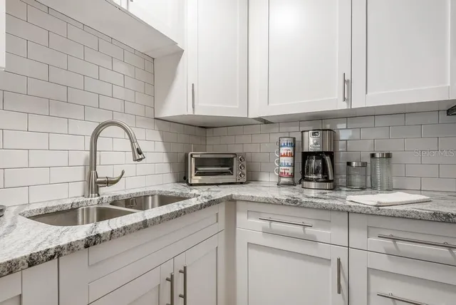 a kitchen with granite countertop white cabinets and a sink