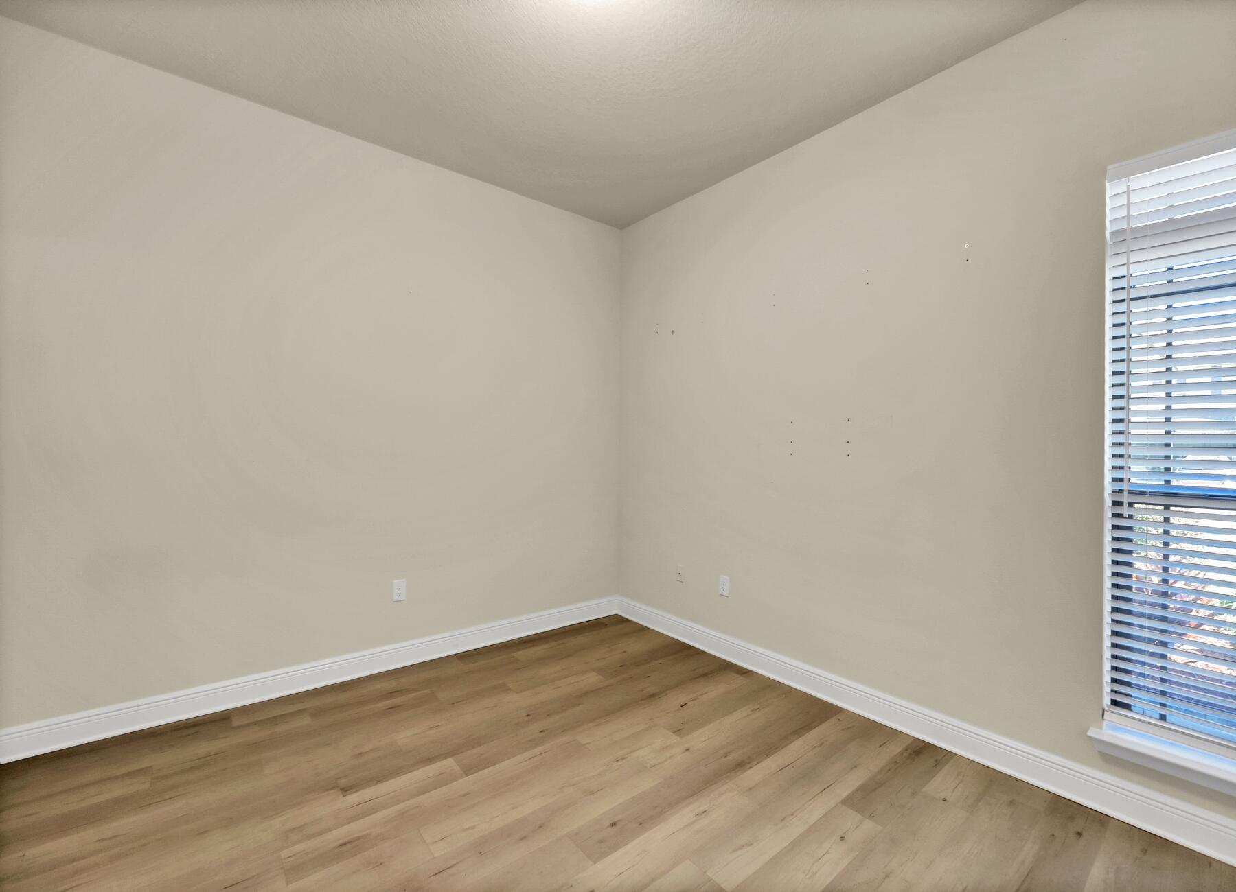 3639 Ranch Drive Crestview, FL 32539 - Photo 13 of 84 a view of an empty room with wooden floor and a window