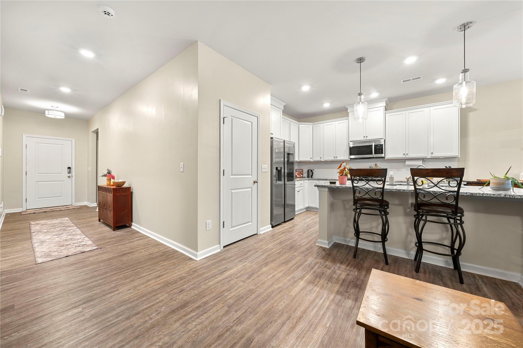 1990 Ambrose Way Denver, NC 28037 - Photo 10 of 40 a kitchen with stainless steel appliances kitchen island granite countertop a refrigerator a stove top oven and a dining table with wooden floor