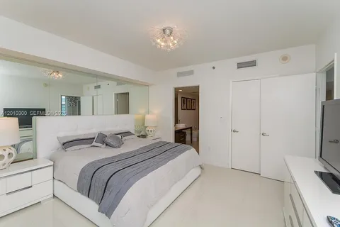 a spacious bedroom with a bed and a chandelier