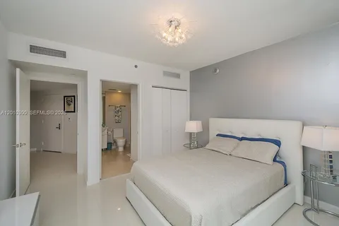a bedroom with a large bed and a chandelier