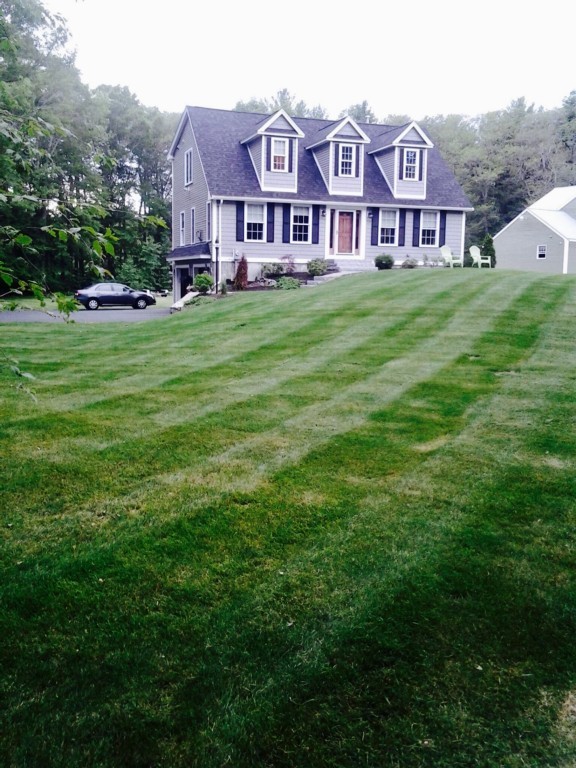 a view of a big house with a big yard and large trees