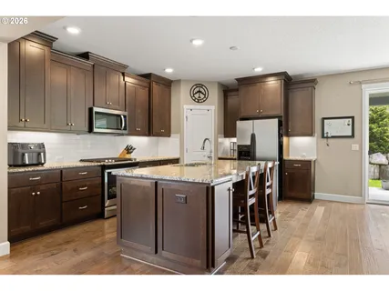 a kitchen with stainless steel appliances granite countertop a refrigerator a sink a stove a microwave and island