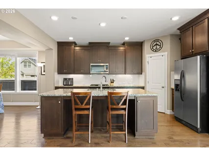 a kitchen with stainless steel appliances granite countertop a refrigerator a stove a sink and a microwave