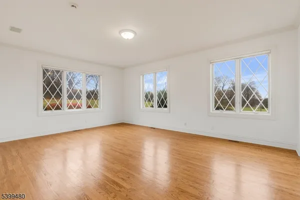 a view of an empty room with window and wooden floor