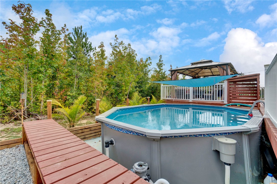 2655 State Rd S-4-108 Anderson, SC 29624 - Photo 28 of 37 An inviting backyard pool is bordered by wooden decking against a scenic tree-lined backdrop.