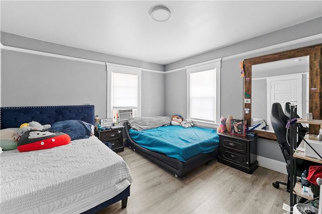 a bedroom with bed a large window and wooden floor