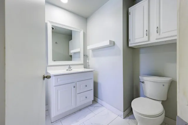 a bathroom with a toilet a sink a vanity and mirror