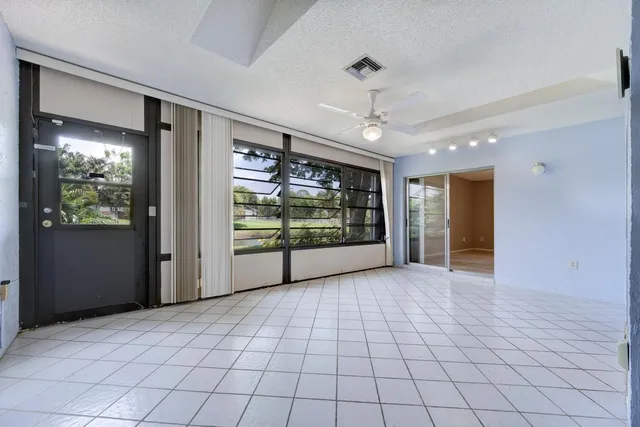 a view of an empty room with window and chandelier