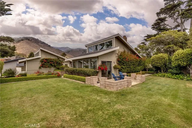 a front view of house with yard and trees in background
