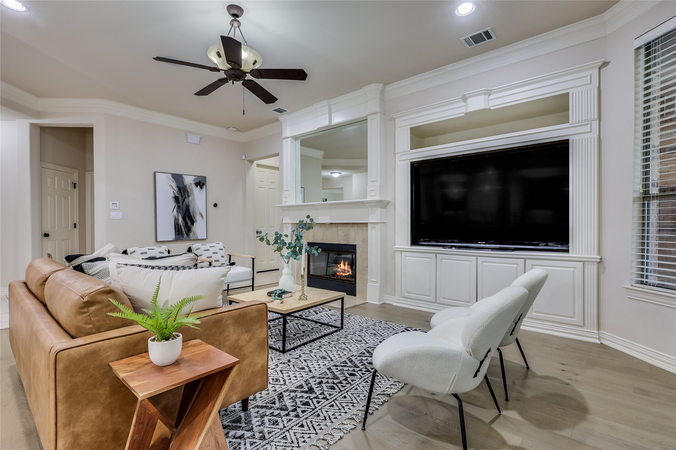 408 Ridgetop Bend Cedar Park, TX 78613 - Photo 8 of 40 A well-lit living space features a cozy fireplace, built-in entertainment center, and light wood flooring.